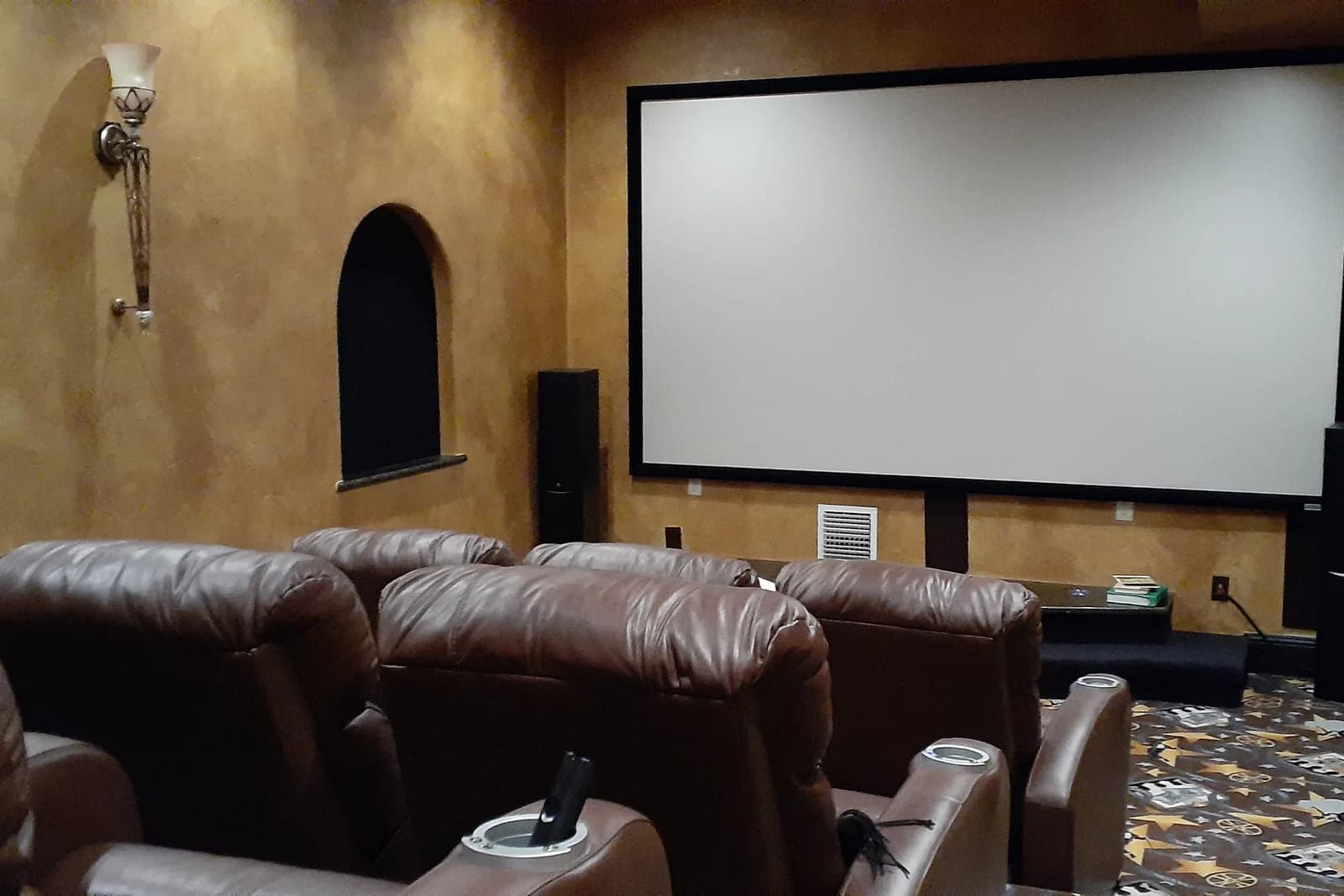 Cinema room with gold plaster walls, film-reel patterned carpet and tiered seating