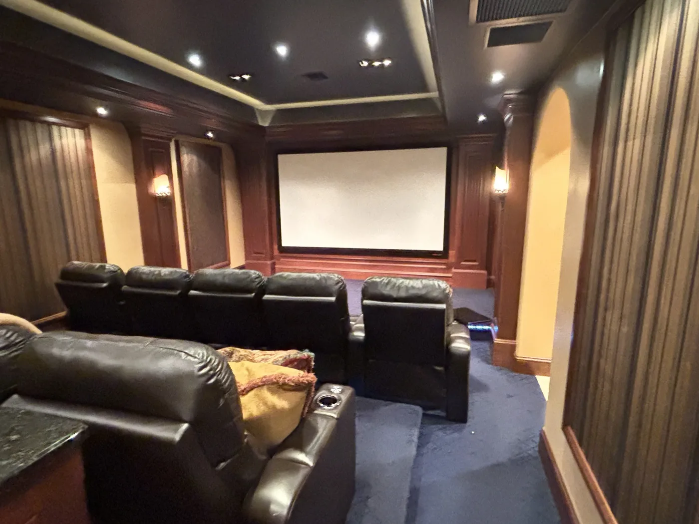 Cinema room with dark wood panelling, striped drapes, wall sconces and a projection screen