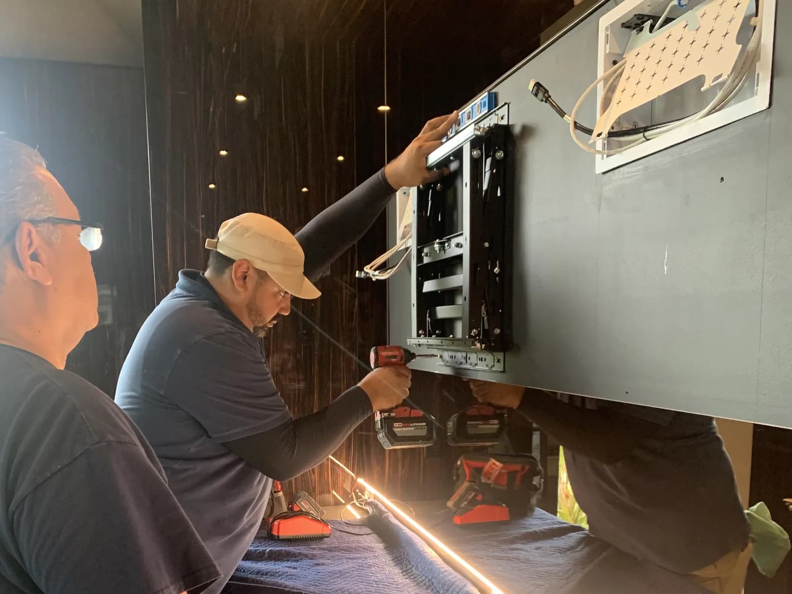 Two technicians level and fasten a display mounting bracket during an installation