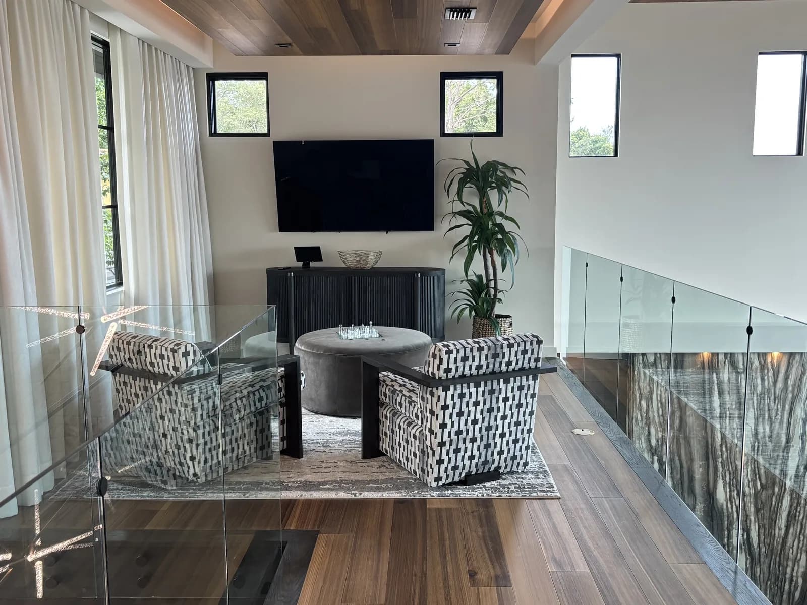 Loft landing in a modern home with a wall-mounted display and a glass railing